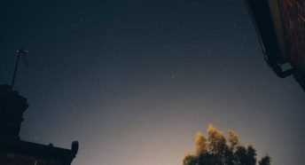 Night sky with stars over house roof and tree